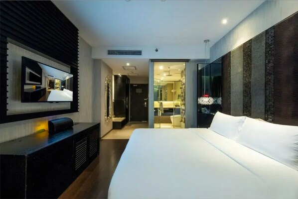 A modern hotel room with a large bed, a flat-screen TV mounted on the wall, and a walk-in closet.