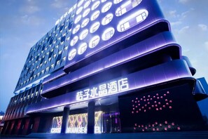 A multi-story hotel with a modern design, featuring illuminated windows and a prominent signage. - Crystal Hotel  Beijing JiuXianQiao (Beijing)
