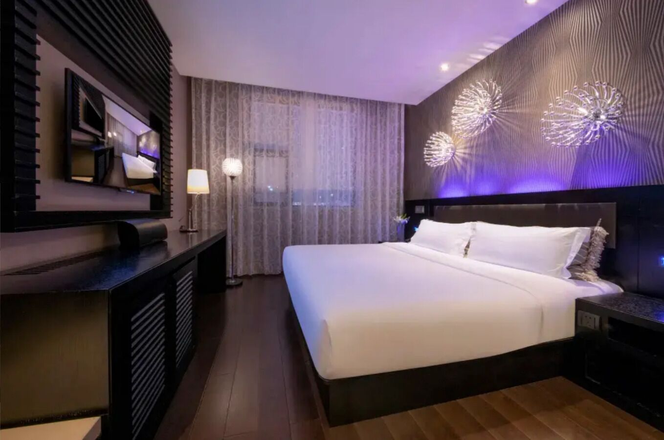 Una habitación de hotel moderna con una cama grande, un escritorio y un televisor.