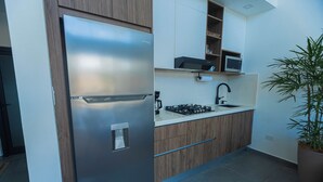 A modern kitchen with a stainless steel refrigerator, wooden cabinets, a microwave, and a sink.