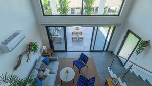 A spacious living area with a sofa, two chairs, a coffee table, and a staircase with a glass railing.