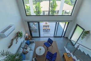 A spacious living area with a sofa, two chairs, a coffee table, and a staircase with a glass railing.