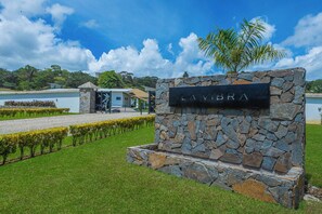 A stone sign with 'LAVIBRA' written on it, surrounded by a well-maintained lawn and a palm tree. - Pool, Yoga Studio -Private La Vibra Resort Villa 1 (Langostino)