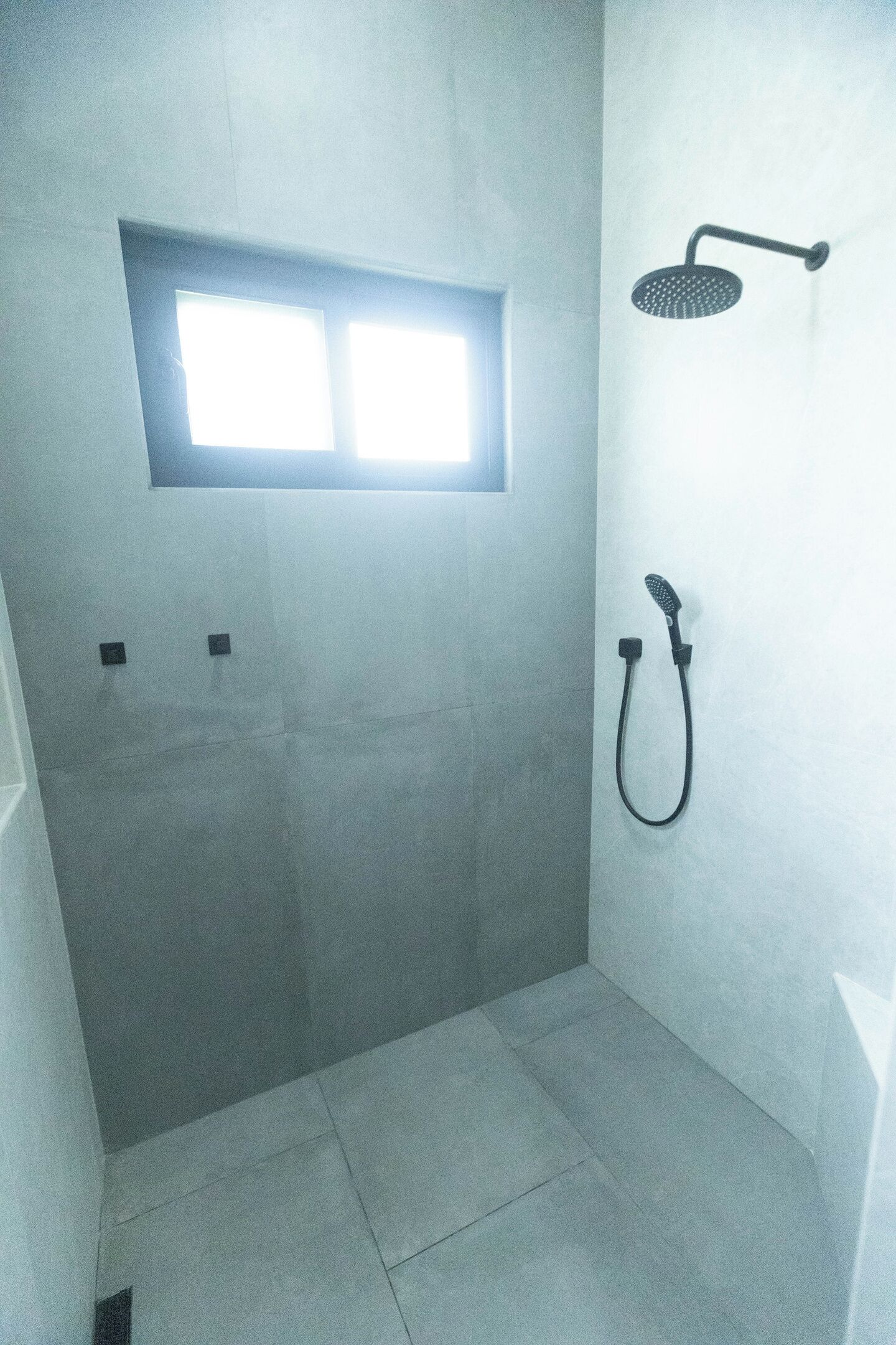 Une salle de bain avec une douche, une petite fenêtre et un porte-serviettes.