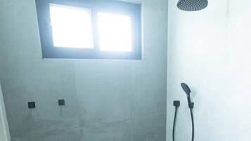 Une salle de bain avec une douche, une petite fenêtre et un porte-serviettes.