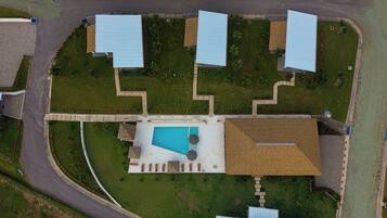 Vue aérienne d’une propriété dotée d’une piscine, de plusieurs bâtiments aux toits bleus et d’une pelouse bien entretenue.