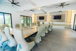 A conference room with a long table, multiple chairs, ceiling fans, and a TV mounted on the wall. - Pool, Yoga Studio -Private La Vibra Resort Villa 3 (Langostino)
