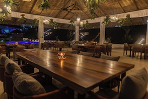 An outdoor dining area with wooden tables and chairs, hanging plants, and a thatched roof. - Pool, Yoga Studio -Private La Vibra Resort Villa 3 (Langostino)