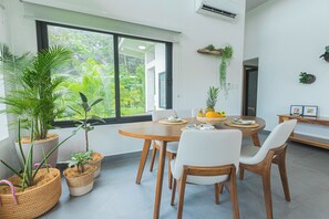 A dining area with a round wooden table, white chairs, and potted plants. - Pool, Yoga Studio -Private La Vibra Resort Villa 4 (Langostino)