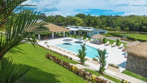 A resort with a swimming pool, lounge chairs, and a thatched-roof structure. - Pool, Yoga Studio -Private La Vibra Resort Villa 4 (Langostino)