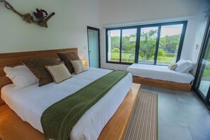 A bedroom with a large bed, a smaller sofa bed, a view of greenery, and a door. - Pool, Yoga Studio -Private La Vibra Resort Villa 4 (Langostino)