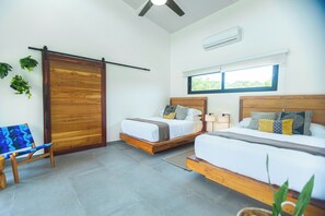 Ein modernes Schlafzimmer mit zwei Betten, einer Schiebetür, einer Sitzbank und einem Fenster.
