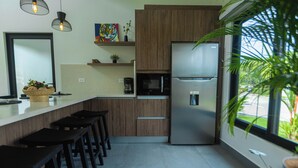 Une cuisine moderne avec des meubles en bois, un réfrigérateur en acier inoxydable, un four à micro-ondes et une grande fenêtre.