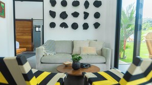 Un salon comprenant un canapé, des fauteuils, une table basse et un mur décoré de différents objets.