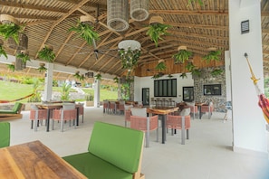 An outdoor dining area with wooden tables and chairs, hanging plants, and a stone wall. - Pool, Yoga Studio, Private-La Vibra Resort Villa 6 (Langostino)