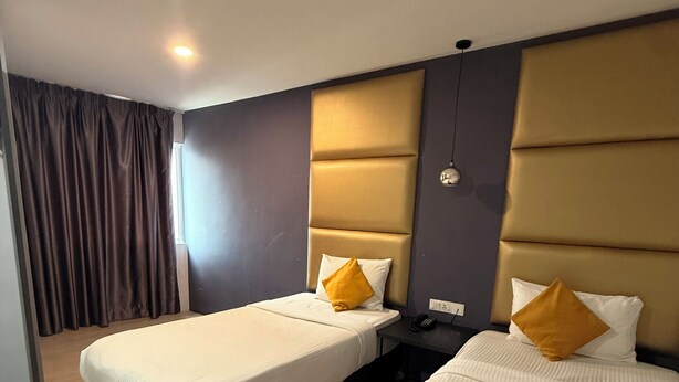 A hotel room with two beds, each with a headboard, a bedside table with a phone, and a window with curtains. - The Wow Boutique (George Town)