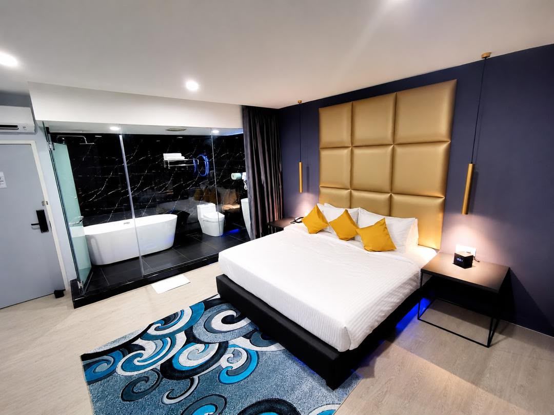 Una habitación de hotel moderna con una cama grande, un baño independiente con bañera y cabina de ducha de vidrio.