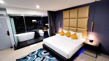 Una habitación de hotel moderna con una cama grande, un baño independiente con bañera y cabina de ducha de vidrio.