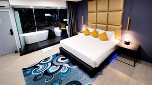 A modern bedroom with a large bed, a bathroom with a bathtub, and a glass-enclosed shower area. - The Wow Boutique (George Town)
