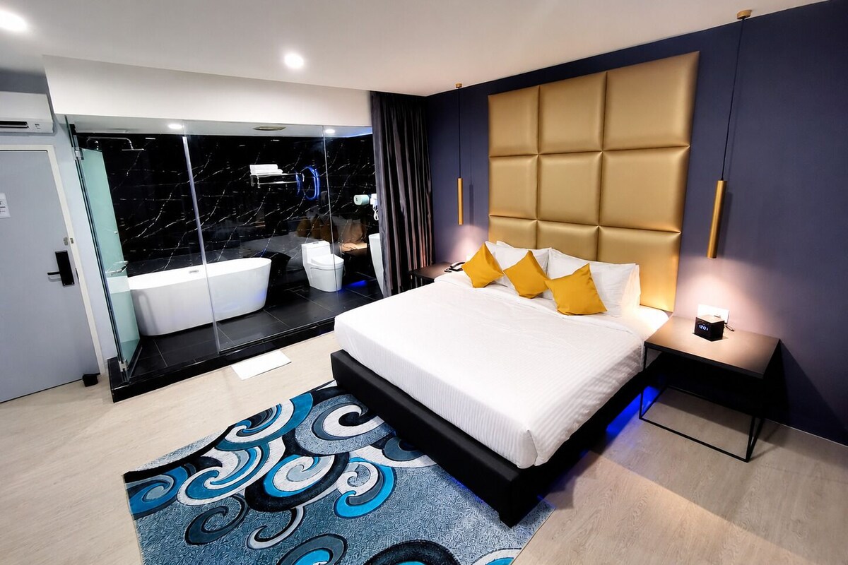 A modern bedroom with a large bed, a bathroom with a bathtub, and a glass-enclosed shower area.