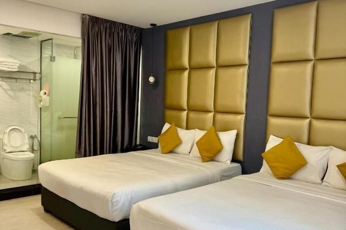 A hotel room with two beds, a shower area, and a toilet.