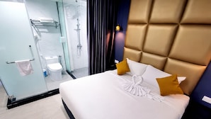A hotel room with a bed, a bathroom, and a glass shower enclosure. - The Wow Boutique (George Town)