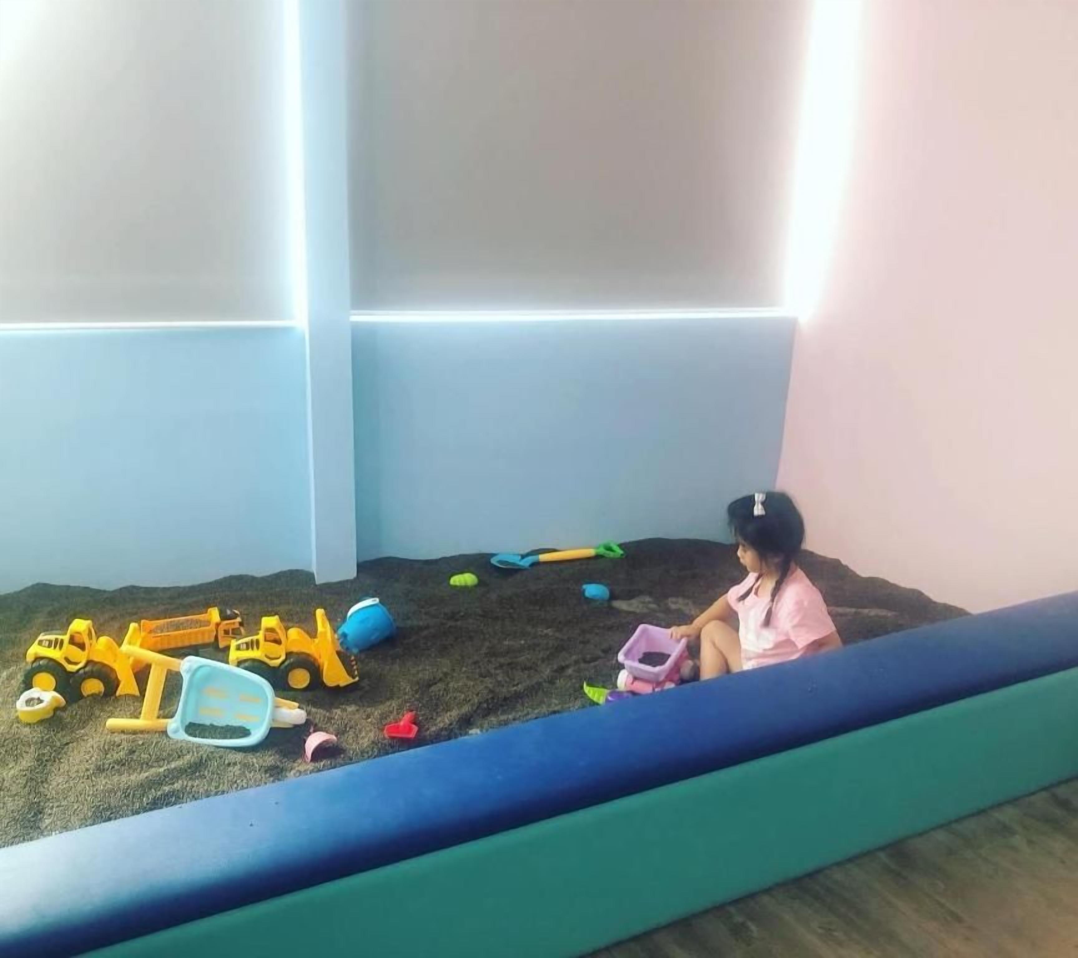 Niño jugando con juguetes en un arenero.