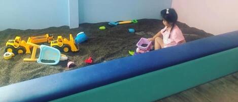 Niño jugando con juguetes en un arenero.