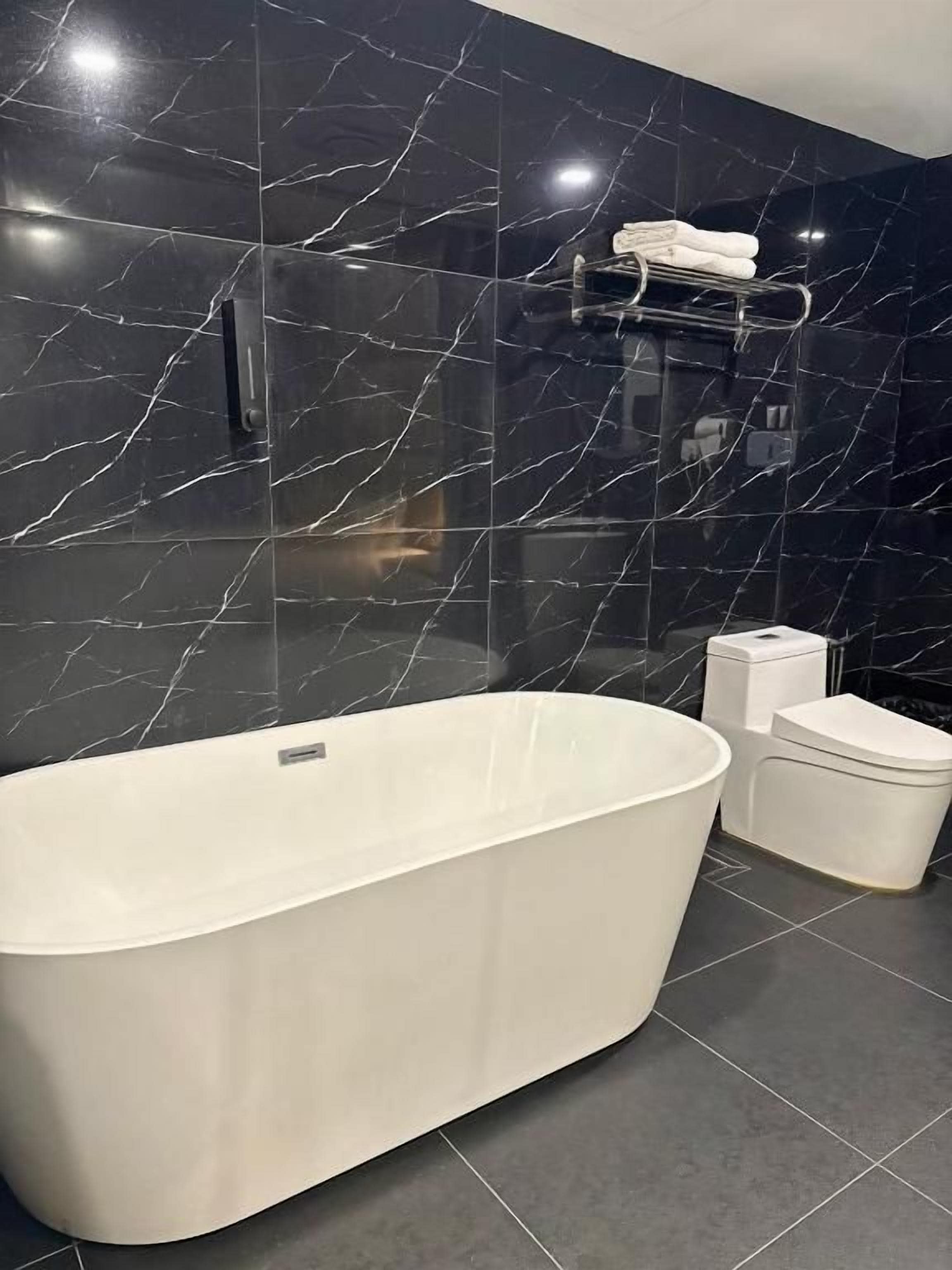 A modern bathroom with a freestanding bathtub, a toilet, and a towel rack.