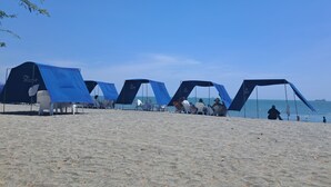 A beach with several blue tents and white chairs. - Suite Apartment | Ocean View | Infinity Pool | Rooftop | Jacuzzi (Santa Marta)