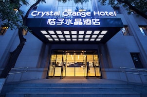 The Crystal Orange Hotel entrance with a modern facade, glass doors, and a sign in both English and another language.