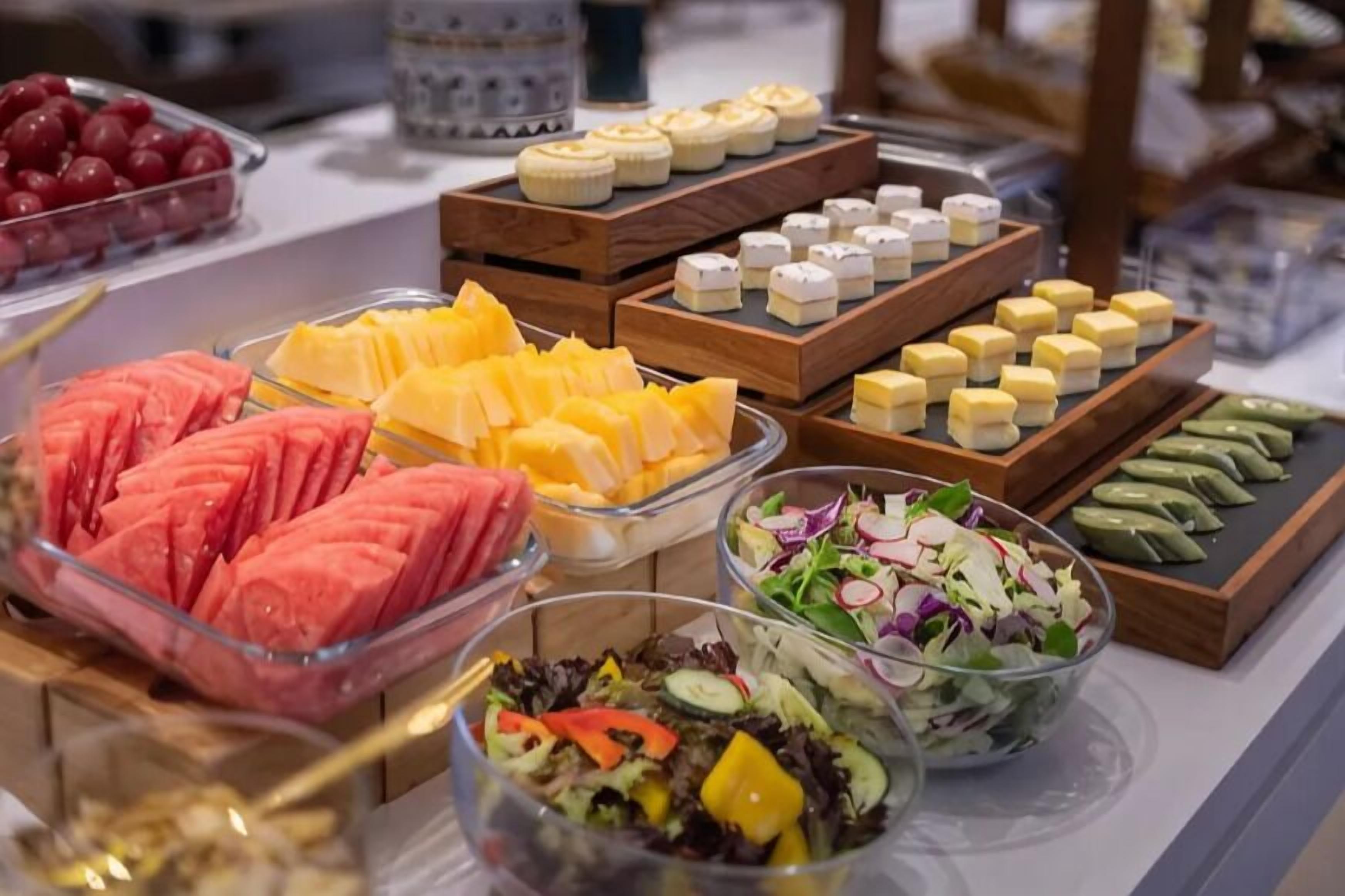 A buffet with various food items including fruits, cheeses, and salads.