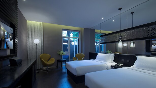 A hotel room with two beds, a desk, a chair, a mirror, and a window with a view of the outside. -  Crystal Orange Hotel, Beijing Qianmen (Beijing)
