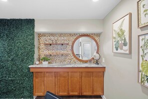 A kitchen with a wooden countertop, a backsplash with a mosaic pattern, a round mirror, and a green wall. - Family Friendly, Pizza Oven & BBQ, Near Downtown (St. Augustine)