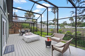 A covered outdoor deck with a bed, chairs, and a small table. - Family Friendly, Pizza Oven & BBQ, Near Downtown (St. Augustine)