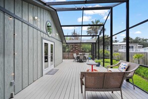 A covered outdoor patio with a wooden deck, wicker furniture, and a view of the backyard. - Family Friendly, Pizza Oven & BBQ, Near Downtown (St. Augustine)