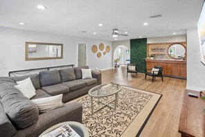 A modern living room with a grey sofa, a glass coffee table, and a patterned rug. - Family Friendly, Pizza Oven & BBQ, Near Downtown (St. Augustine)