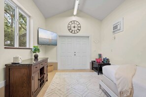 A bedroom with a bed, a TV, a clock, and a window. - Family Friendly, Pizza Oven & BBQ, Near Downtown (St. Augustine)