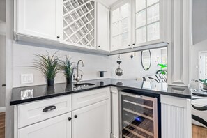 Eine Küche mit weißen Schränken, einer schwarzen Arbeitsplatte und einem eingebauten Weinkühlschrank.