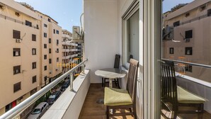 Un balcon avec une table et des chaises, donnant sur un paysage urbain composé de nombreux bâtiments.