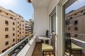 A balcony with a table and chairs, overlooking a cityscape with multiple buildings. - Wave Stay Studio Durr s Waterfront (Durrës)