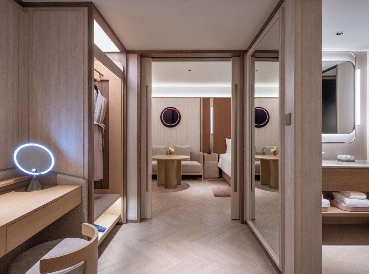 Ein Hotelzimmer mit Schminktisch, rundem Spiegel, einem Bett, einer Couch und einem kleinen Tisch.