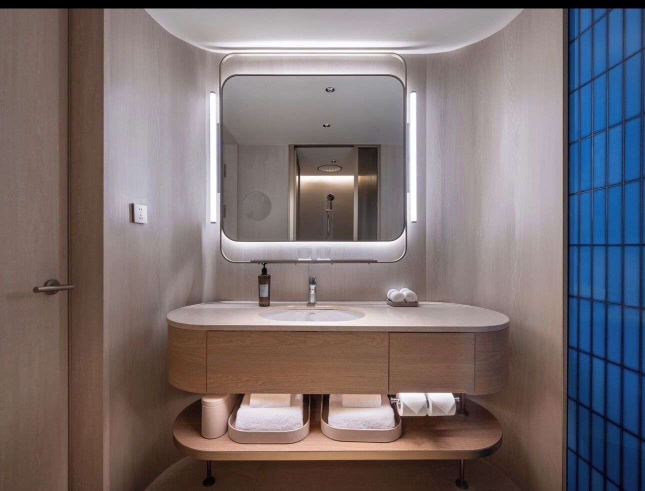 A modern bathroom with a round sink, a mirror, and a towel rack.