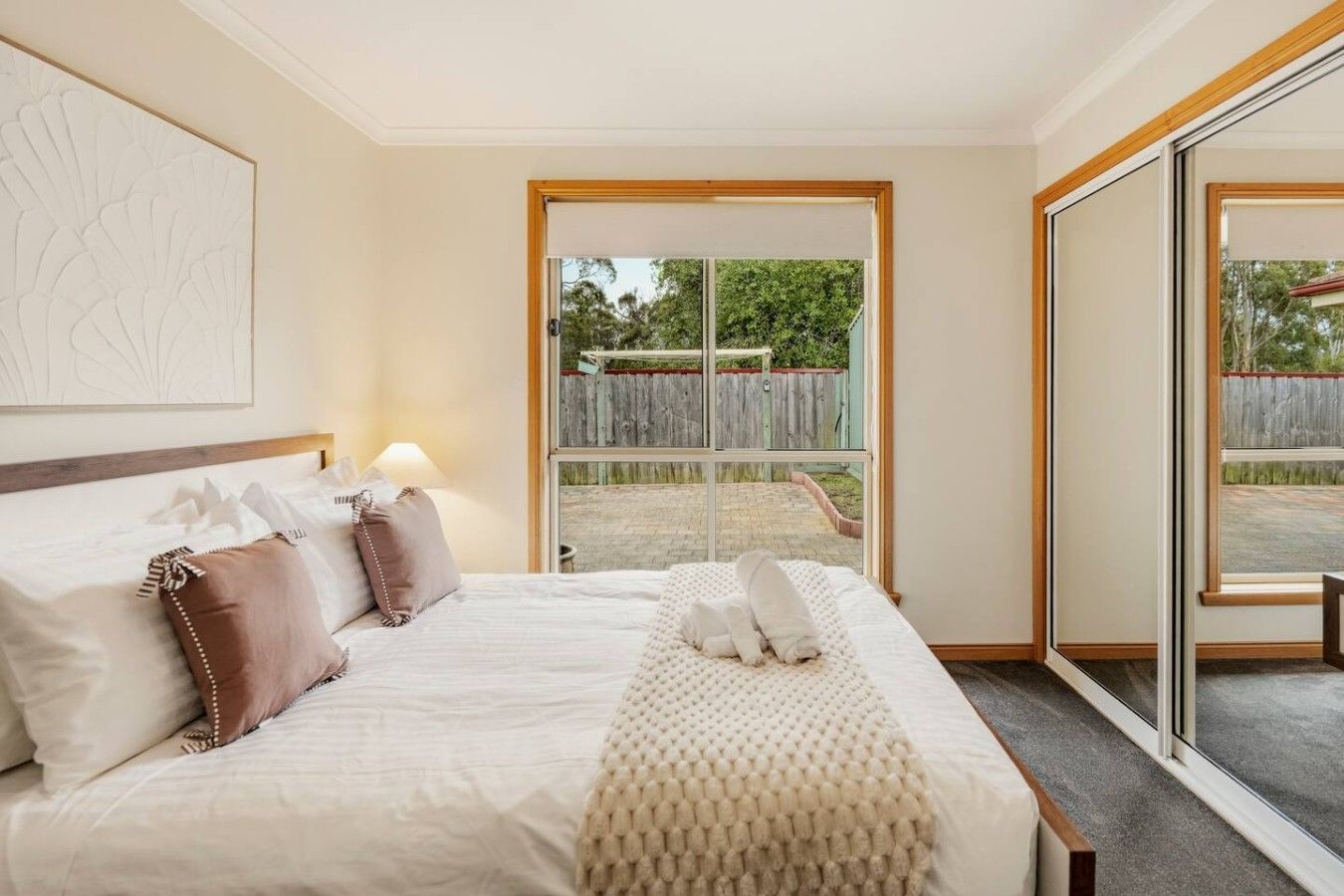 A hotel room with a bed, a large window, and a view of the outdoors.