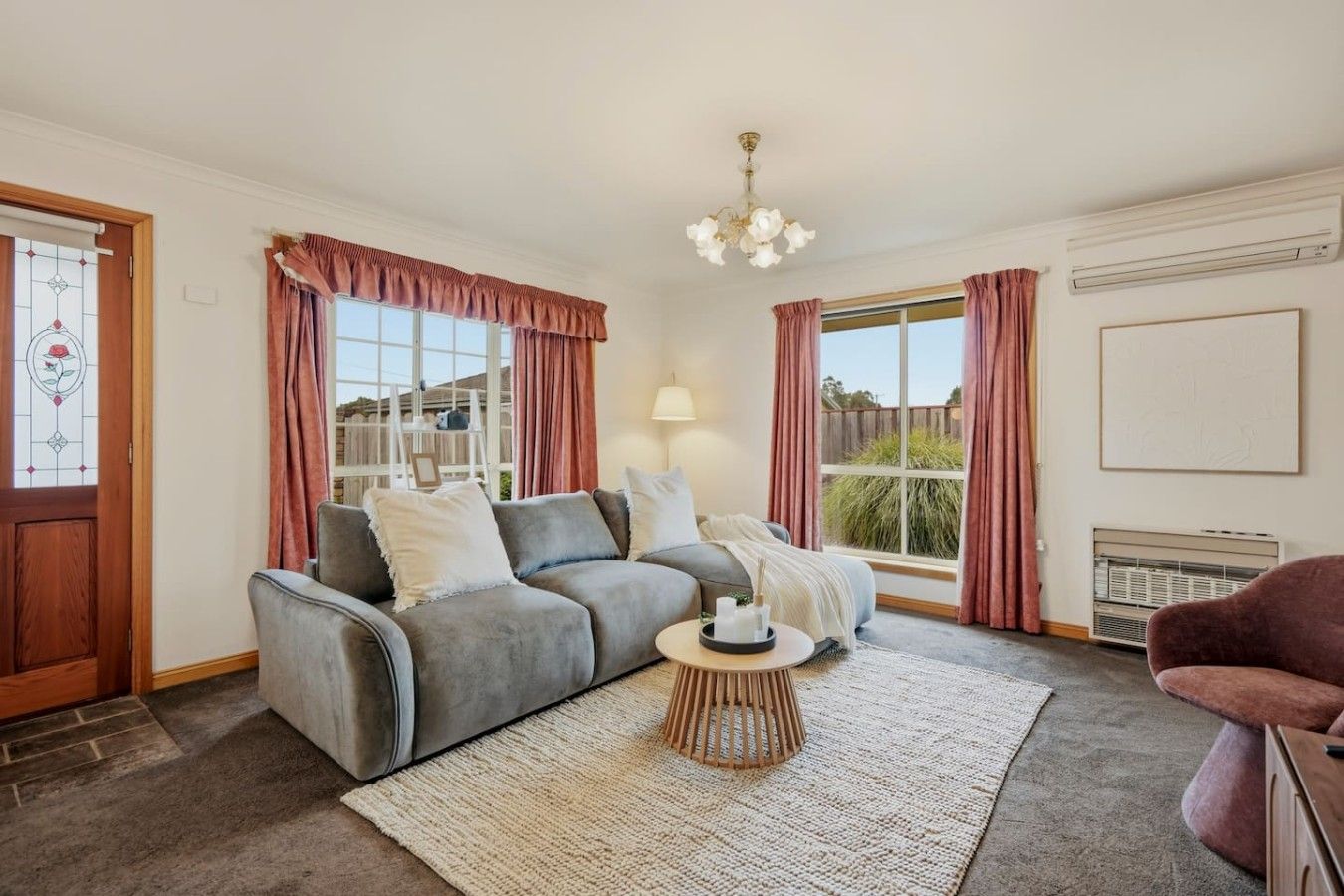 A living room with a grey sofa, a coffee table, and a view of the outdoors.