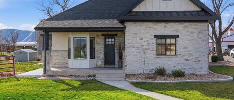 A two-story house with a stone facade, a dark roof, and a front porch.