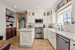 A modern kitchen with white cabinetry, a stainless steel stove, and a microwave.