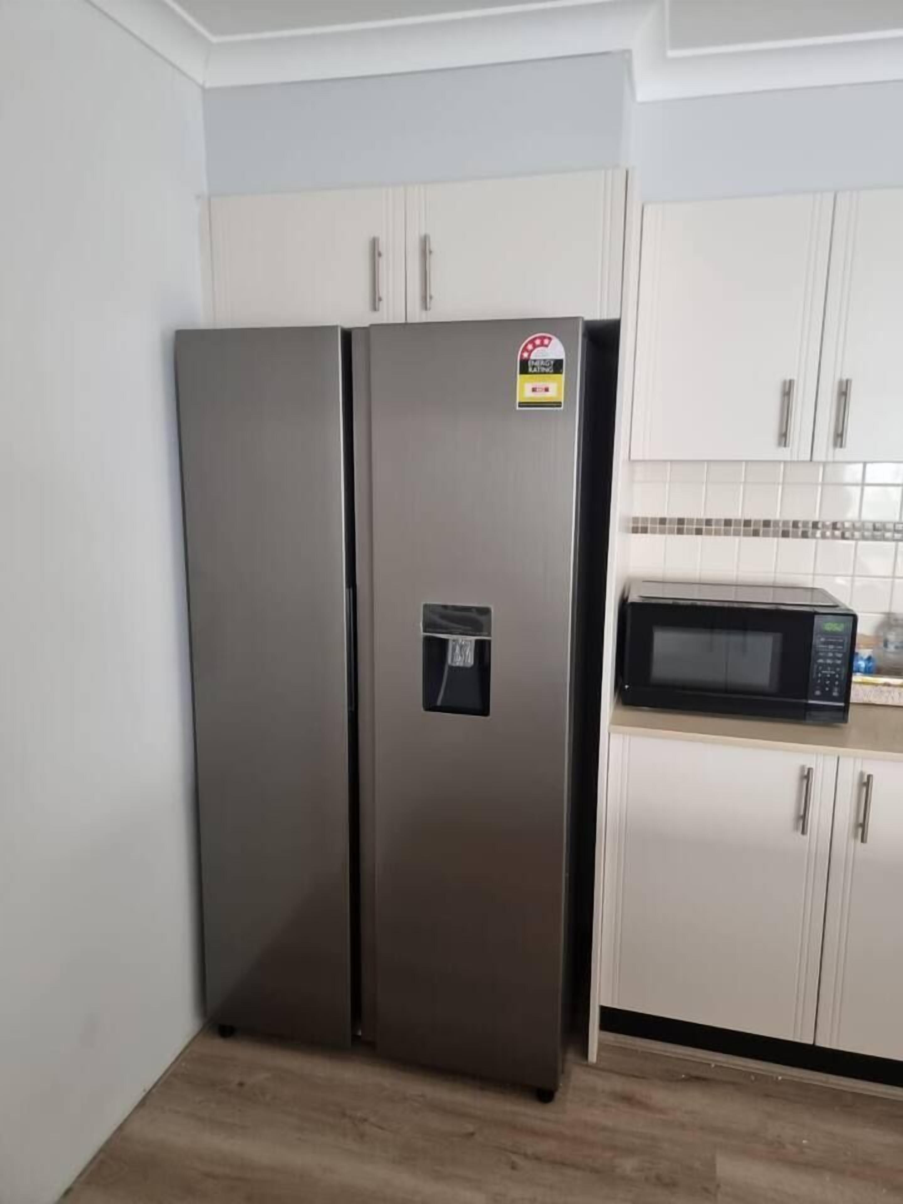 A kitchen with a stainless steel refrigerator and a microwave on the countertop.