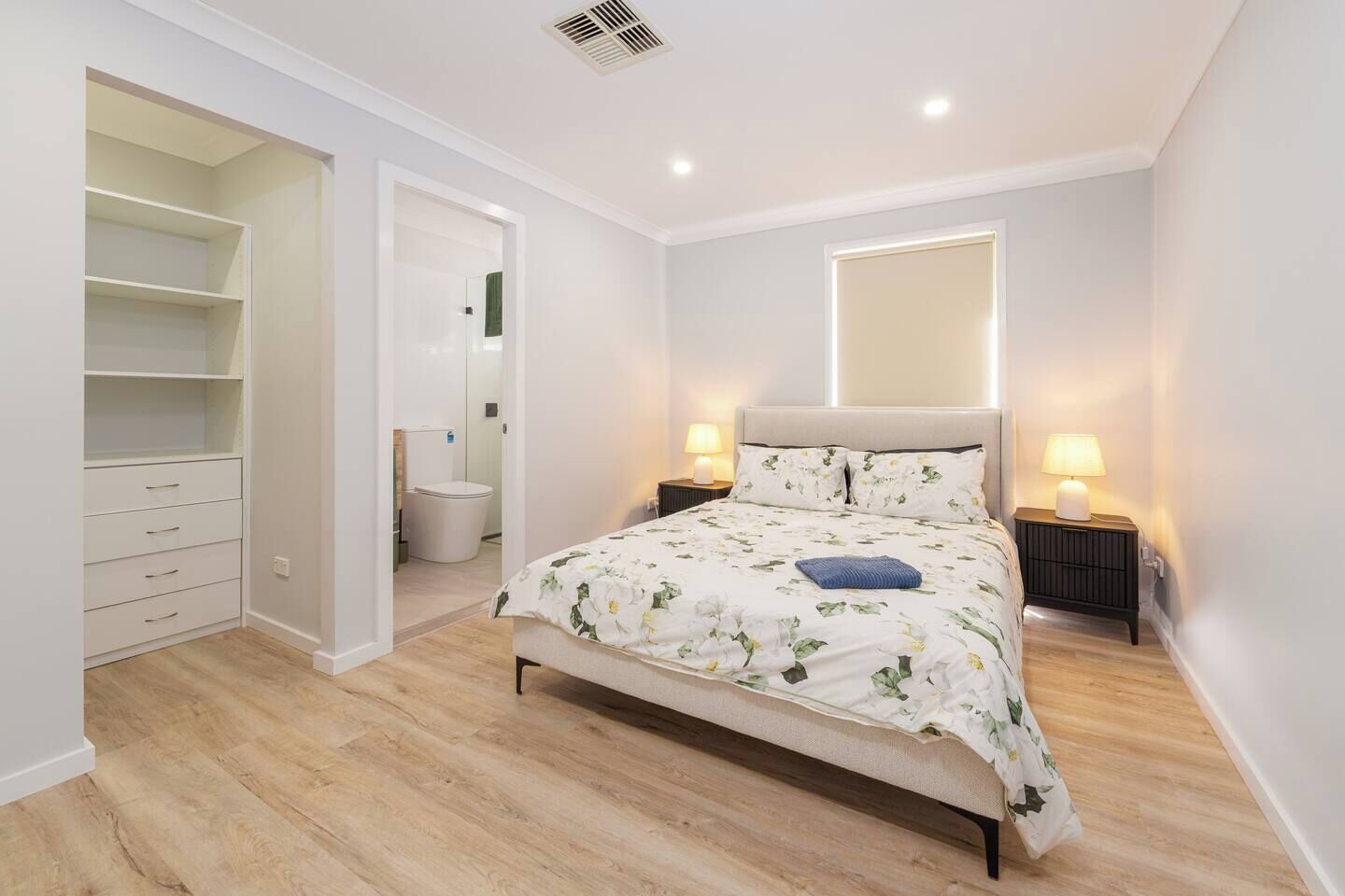 A bedroom with a bed, bedside tables, a wardrobe, and a bathroom.