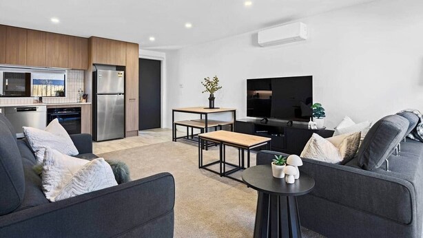 A modern living room with a sofa, a coffee table, and a flat-screen TV. - Luxury on Gloucester (Christchurch)